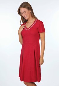 Rotes, kurzärmliges Kleid mit V-Ausschnitt und floraler Stickerei am Ausschnitt. Der Stoff hat eine leicht strukturierte Oberfläche und einen gefalteten Rock.