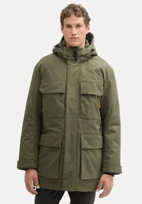 Zelená zateplená parka s kapucňou, so štyrmi veľkými prednými vreckami, zipsovým zapínaním a nastaviteľnými manžetami. Textúrovaná, vodoodpudivá tkanina.