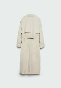 Beżowy płaszcz trencz o kroju dwurzędowym, z długimi rękawami i regulowanymi mankietami. Posiada pasek oraz luźny, opadający tył.