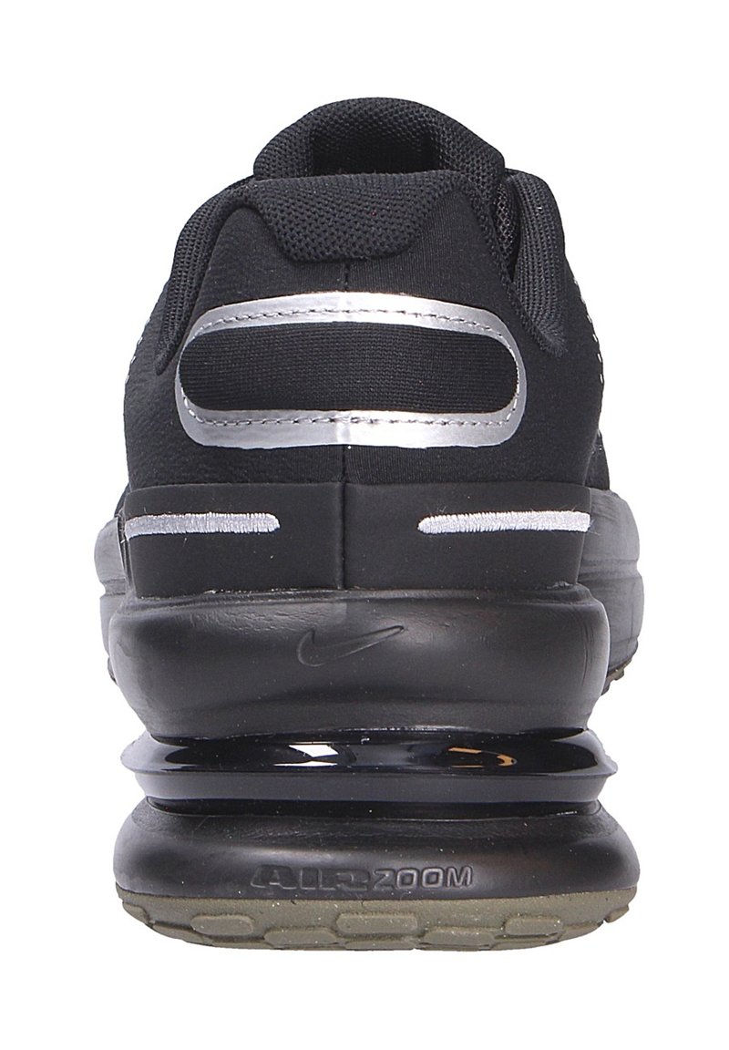 Zapatilla deportiva negra con parte superior de malla, acentos plateados, suela negra gruesa y amortiguación de aire visible; diseño minimalista con material texturizado.