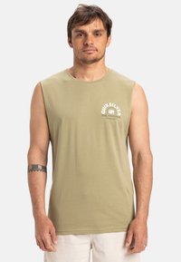 Olive zaļā bez piedurknēm T-krekls, kas izgatavots no maigas auduma, ar apaļu apkakli un baltu Quiksilver logotipu uz krūšu.