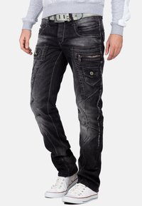 Zwarte denim jeans met een slim fit, voorzien van contrasterende witte stiksels, meerdere ritszakken en een gestructureerde afwerking.