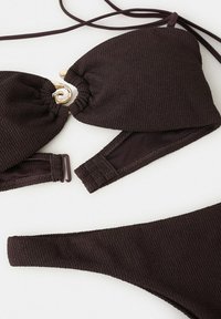 Bikini en tissu texturé marron foncé avec détail en anneau doré sur le haut et bretelles arrière réglables.