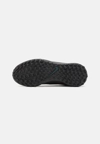 Semelle de chaussure de sport noire avec un motif texturé, présentant un talon lisse et courbé et un logo Nike bleu foncé contrastant.