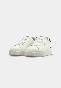 Weisse Ledersneaker mit Schnürdesign, abgerundeter Zehenpartie und dicker, cremefarbener Sohle. Schwarzer Absatzakzent mit "GUESS"-Logo an der Seite.