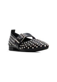 Zapato plano negro con superficie texturizada adornada con tachuelas plateadas, una correa con hebilla en la parte delantera y un diseño de tacón bajo.