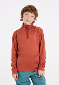 Roodbruine half-zip lange mouw top van zachte stof, met hoge kraag en logo-detail op de borst, gecombineerd met teal broek.