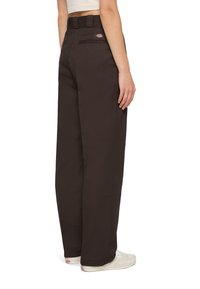 Mörkbruna vida byxor med hög midja, sidfickor och en logotyp-patch på baksidan. Slät tyg med en strukturerad passform.