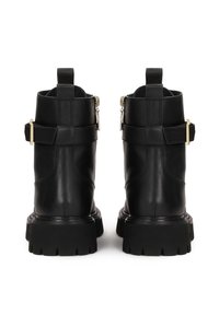 Botine din piele neagră, până la gleznă, cu un finisaj texturat, având fermoare laterale, curele ajustabile și talpa groasă cu prindere.