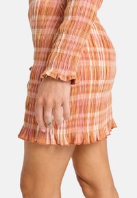Robe ajustée à manches courtes dans des nuances d'orange et de rose, présentant un design plissé texturé et un ourlet à volants pour plus de détail.