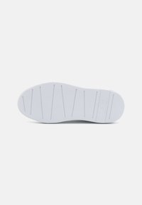 Suela de zapato de goma blanca con una superficie texturizada y patrones de banda de rodadura lineales para mayor agarre. Bordes suaves y diseño de punta redondeada.