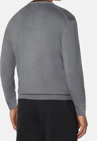 Šedý svetr s dlouhým rukávem, texturovaným pletením, žebrovanými manžetami a lemem, navržený s jednoduchým, čistým střihem a kulatým výstřihem.