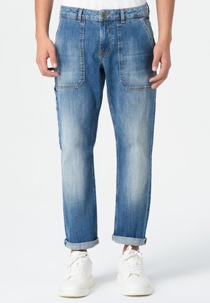 Jean droit bleu clair avec une finition délavée, design à cinq poches et ourlets retroussés, associés à des baskets blanches.