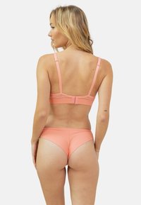 Ensemble de lingerie corail avec un design en dentelle au dos, des bretelles ajustables, un tissu doux et une texture lisse. La vue arrière montre un bas de style bikini.
