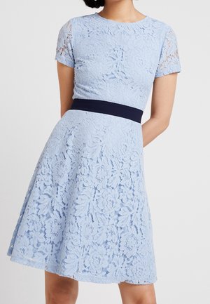 Jasnoniebieska koronkowa sukienka z krótkimi rękawami i dopasowanym ciemnogranatowym paskiem w talii, spódnica do kolan, kwiatowy wzór koronki.