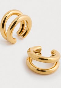 Złote kolczyki w kształcie obręczy z g�ładkim, błyszczącym wykończeniem, posiadające skręcony wzór i zaokrąglone krawędzie. Lekka i minimalistyczna stylistyka.