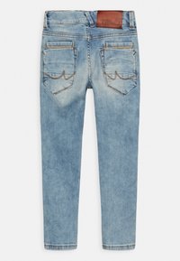 Jean en denim bleu clair avec des détails délavés, deux poches arrière avec des coutures, et une étiquette de marque en cuir marron sur la ceinture.