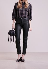 Svarta faux läder skinntights som bärs med en rutmönstrad skjorta med knappar. Accessoriserat med en liten svart handväska och svarta klackskor.