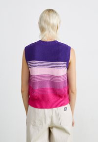 Gebreid mouwloos sweater met horizontale strepen in paars, roze en fuchsia. Geribbelde zoom en halslijn zorgen voor textuur.