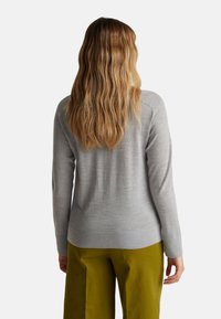 Maglione grigio a maniche lunghe con una texture liscia, scollatura a girocollo e una vestibilità rilassata, abbinato a pantaloni larghi verde oliva.