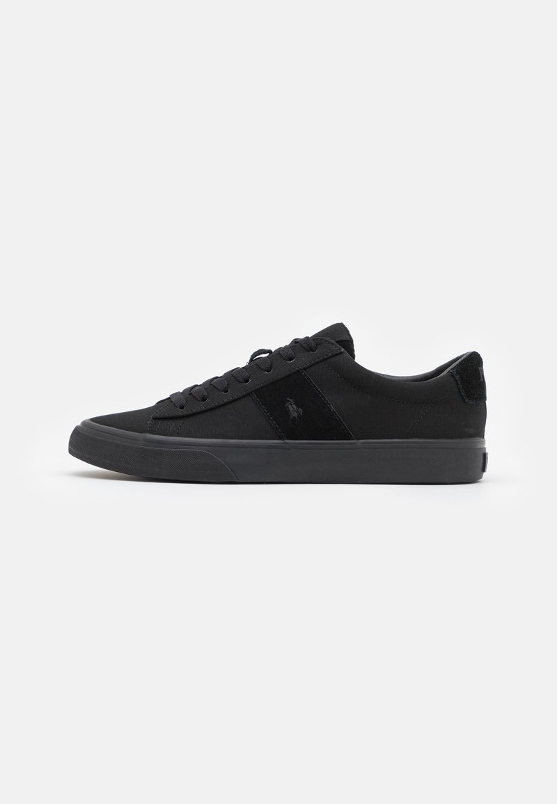 Baskets basses noires avec fermeture à lacets, semelle épaisse et logo discret sur le côté, vues de l’extérieur sur fond blanc.