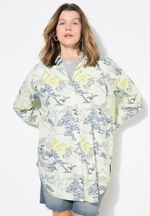 Camisa verde claro de botones con un estampado escénico de árboles, montañas y pájaros en tonos azules y rosas. Corte amplio con mangas largas.