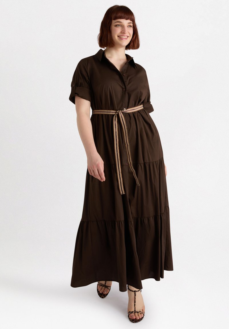 Dunkelbraunes, gestuftes Maxikleid mit kurzen, umgeschlagenen Ärmeln, Knopfleiste und einem gestreiften Gürtel. Der Stoff wirkt glatt mit einem leichten Glanz.