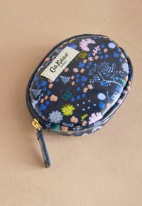 Ümmargune kangaskott, millel on tume sinepikõrgus ja erksad lille- ja majamustrid, kuldne tõmblukk ja väike tumesinine tõmbluku tõukur.