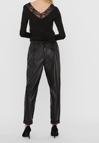 Black long-sleeve top with lace trim at the neckline, paired with black faux leather pants featuring cuffs and elastic waistband.