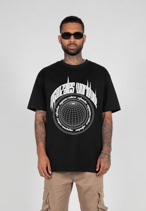 Sort bomulds t-shirt med hvid grafisk print, der viser et globusdesign og tekst. Korte ærmer og en afslappet pasform. Bæres med beige cargo-bukser.