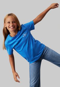 T-shirt di cotone blu brillante con maniche corte e scollatura rotonda. Presenta un piccolo logo bianco nell'area sinistra del petto.