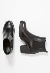 Mustat nilkkurit, jotka on valmistettu sileästä nahasta, paksulla korolla, joustavilla sivupaneeleilla ja teksturoidulla kumipohjalla.