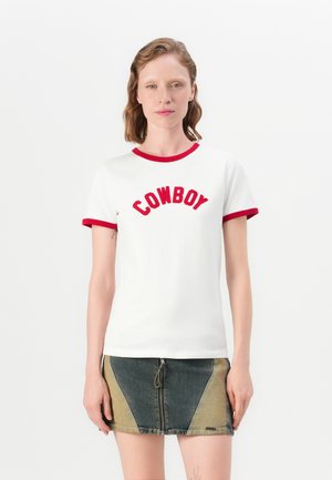 T-shirt en coton blanc avec un col et des manches rouges, portant l'inscription "COWBOY" brodée en rouge vif. Associé à une jupe en jean.