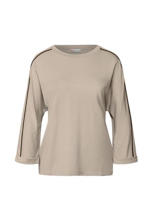 Beige pitkähihaine paita, joka on valmistettu pehmeästä kankaasta. Varustettu käännettävillä hihoilla ja mustilla sivusuojilla kontrastina. Pyöreä kaula-aukko ja rento istuvuus.