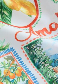 Színes szövet citrus ábrázolásokkal, zöld lombozattal és díszes narancs és kék keretekkel, sima textúrával.