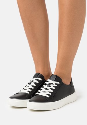 Sneaker in pelle nera con lacci bianchi, punta rotonda e suola in gomma bianca testurizzata. Presenta un logo sulla linguetta e una finitura liscia.