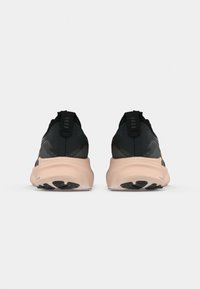 Svart og grå treningssko med mesh-overdel, polstret rosa mellomsåle og teksturert yttersåle. Har en pull-tab bak på hælen.