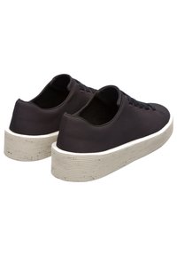 Schwarze Stoff-Sneaker mit einer strukturierten Oberseite, ausgestattet mit einer weißen Gummisohle mit einem geriffelten Muster und schwarzen Akzenten an den Schnürsenkeln.