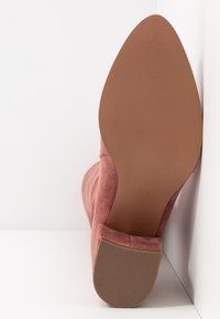 Różowe zamszowe botki za kostkę z wydłużonym noskiem, gładką cholewką i teksturowaną brązową podeszwą. Rozmiar 39 zaznaczony na podeszwie.