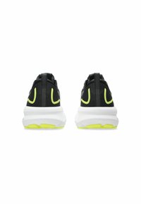 Black athletic shoes with a white sole and neon yellow accents, viewed from the back, showcasing their design and structure.