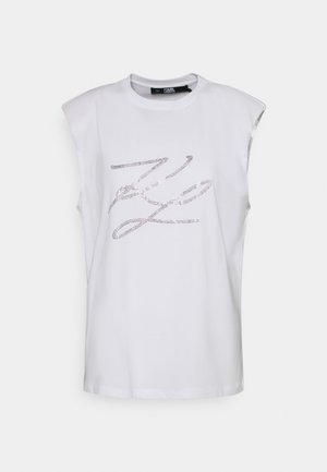 Débardeur blanc avec épaules rembourrées et logo « KL » en strass argenté au centre devant.
