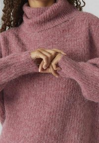 Rosa Rollkragenpullover aus weichem, flauschigem Material mit geripptem Kragen und Bündchen, der eine lockere Passform und eine dezente Textur aufweist.