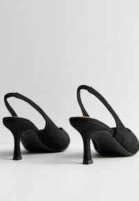 Czarne zamszowe szpilki typu slingback z wysmukłą, kwadratową piętą i otwartym palcem. Cechują się gładką fakturą i minimalistycznym designem.