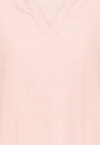 Blouse rose clair avec un décolleté en V, texture douce et lisse, et manches courtes. Design simple sans motifs ni ornements.