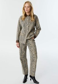Jas en broek set met luipaardprint in beige en grijs, met een knoopsluiting, voorzakken en contrasterende kraag in ruitpatroon.