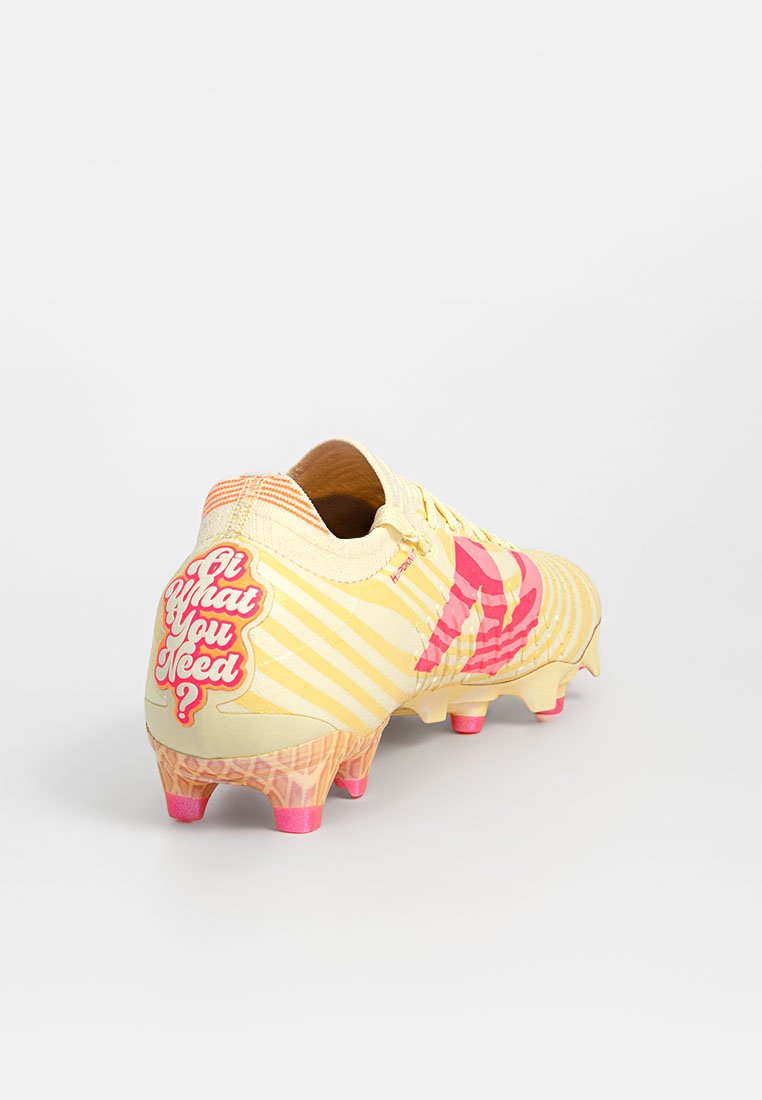 Gele voetbalschoenen met roze accenten en streeppatronen. De hak heeft een grafisch ontwerp met de tekst "Is wat je nodig hebt?" en een gestructureerde zool.