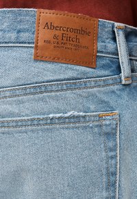 Φωτεινό γαλάζιο τζιν με δερμάτινο ταμπελάκι σε καφέ χρώμα που γράφει "Abercrombie & Fitch." Περιλαμβάνει ραφές στις τσέπες και ελαφρώς φθαρμένη εμφάνιση.