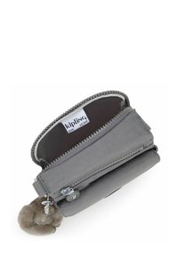 Cartera gris Kipling con cierre de cremallera, que presenta tejido texturizado, dos compartimentos y un adorno de llavero peludo. La etiqueta interior es visible.