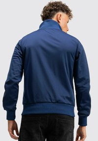 Marineblaue Jacke aus glattem Stoff, mit hohem Kragen und gerippten Bündchen. Sie hat eine lässige Passform und ein schlichtes Design.