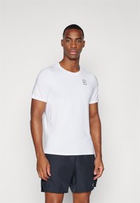 White short-sleeve athletic shirt with a round neckline and a small black logo on the chest, made from lightweight, breathable material.